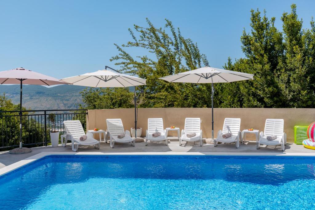 a swimming pool with lounge chairs and umbrellas next to a pool at House with Pool - Ratisevina in Herceg-Novi