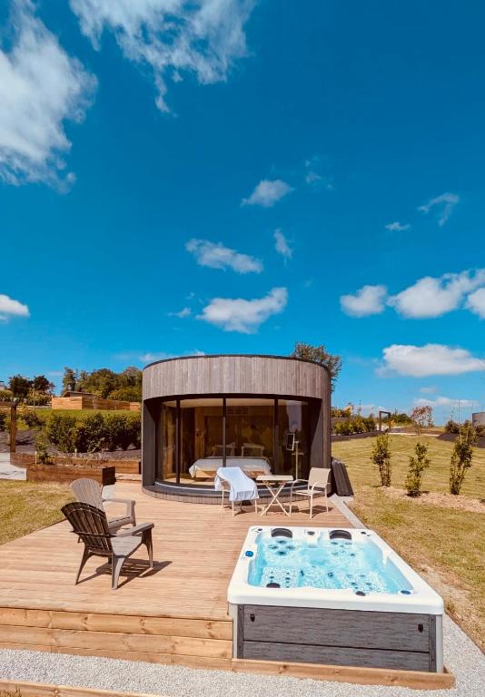 une terrasse en bois avec un bain à remous et une maison dans l'établissement Domaine de Chabrague, à Amou