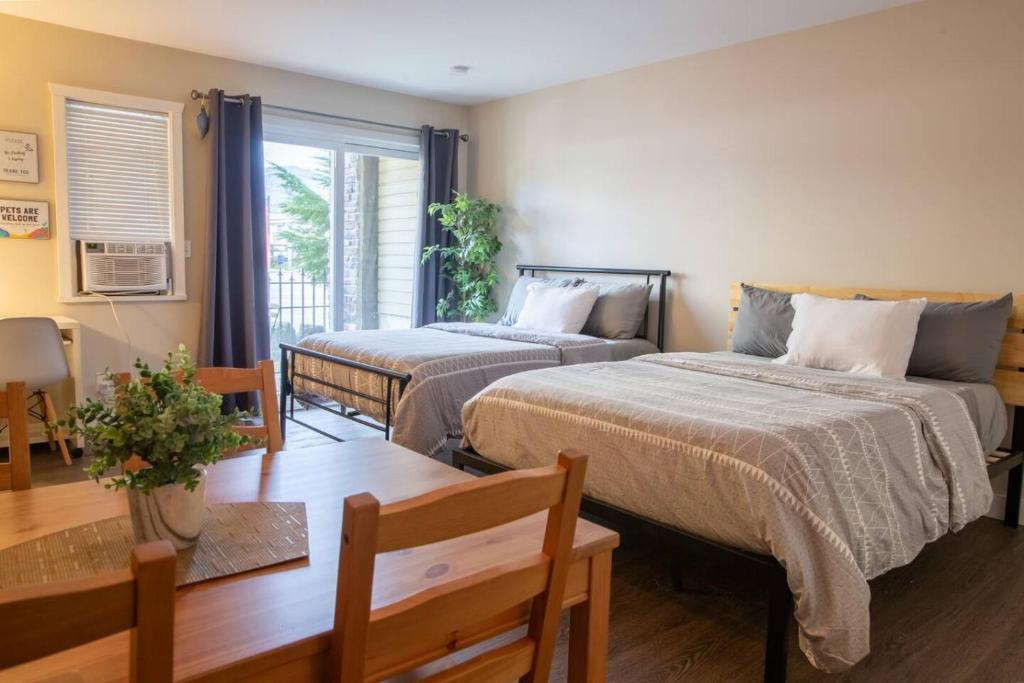 a bedroom with two beds and a table at RiversTail Retreat Pet-Friendly and Steps to The Lake in Harrison Hot Springs