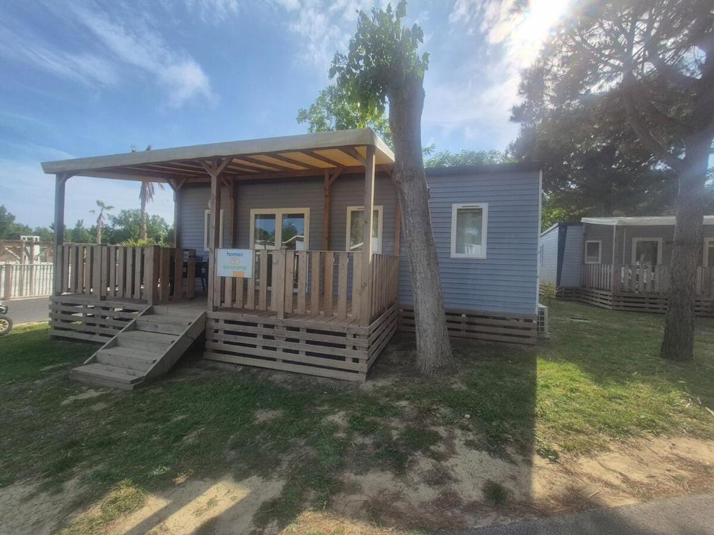 une petite maison avec une véranda et un arbre dans l'établissement Mobil-home camping 5 etoiles, à Valras-Plage