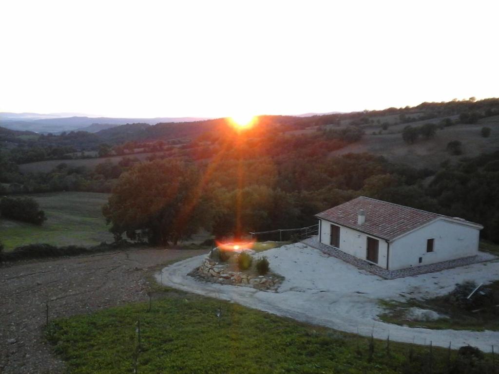 a house in a field with the sunset in the background at Country House La Meria in Catabbio