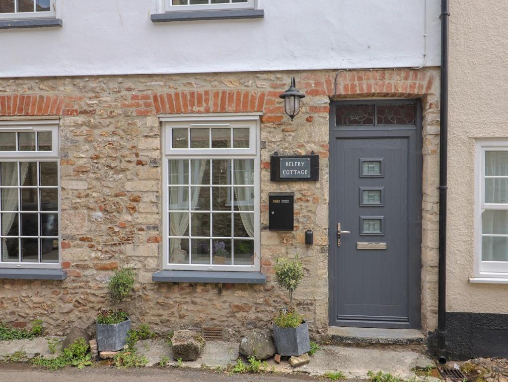 a brick house with a blue door and windows at Belfry Cottage in Colyton