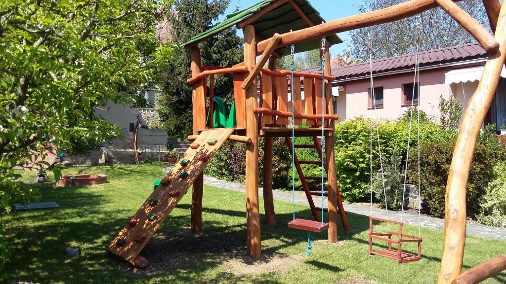 a wooden playground with a slide in a yard at Bungalovy Natura in Trávnica