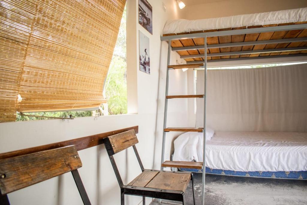 a bedroom with a bunk bed and a chair and a window at Cabañas El Yaguaron in La Porteña