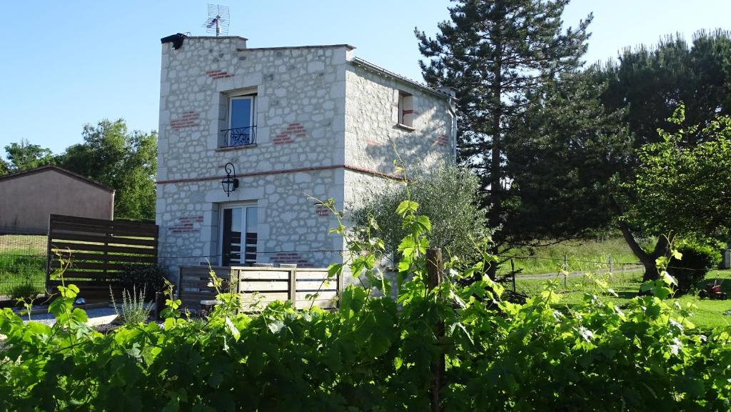 a stone house in a field with trees and bushes at Pigeonnier de campagne in Moncaut