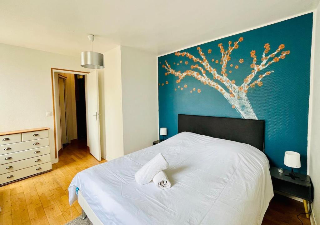 une chambre avec un lit blanc avec un mur bleu dans l'établissement Le charmant Caponière, à Caen