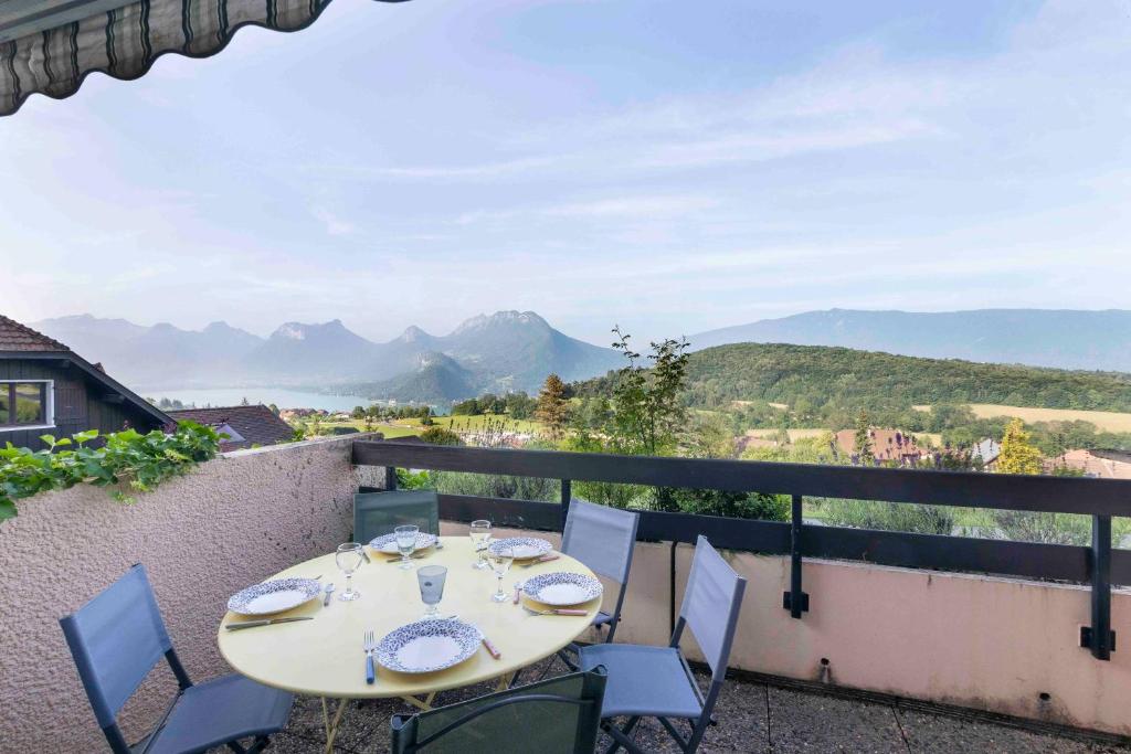 une table et des chaises sur un balcon avec vue sur les montagnes dans l'établissement Cabana & Triplex Bleu d'Annecy - Lake View, Terrace, à Talloires