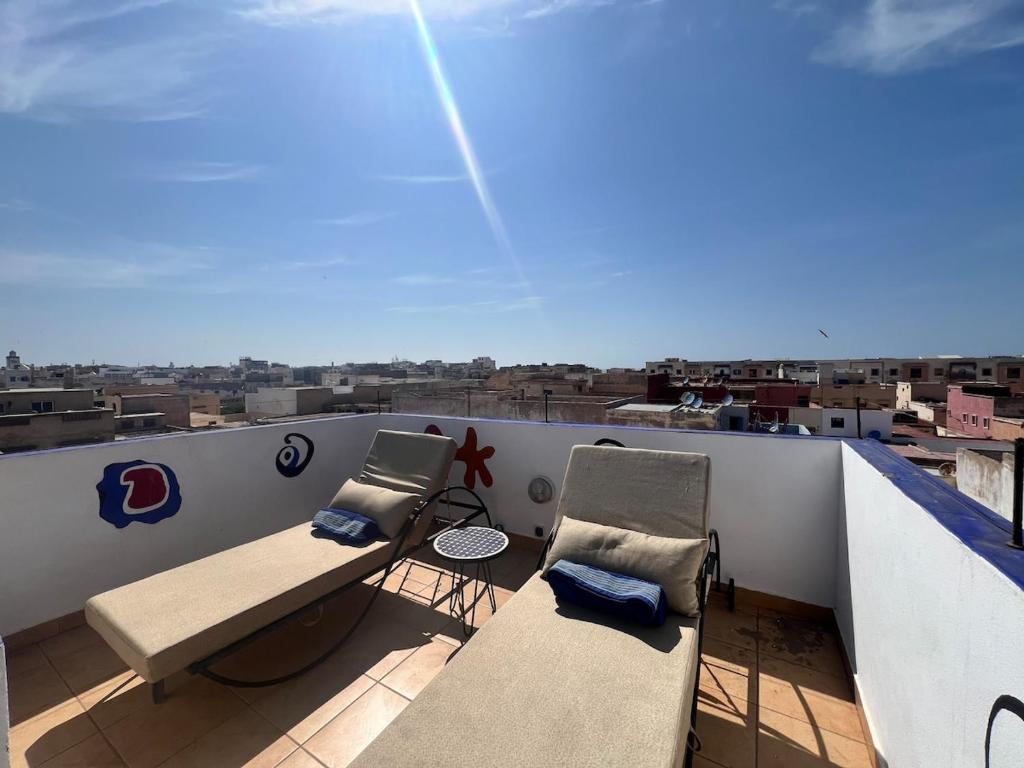 a balcony with two chairs and a bench on a roof at Nour roof top apartment in Essaouira