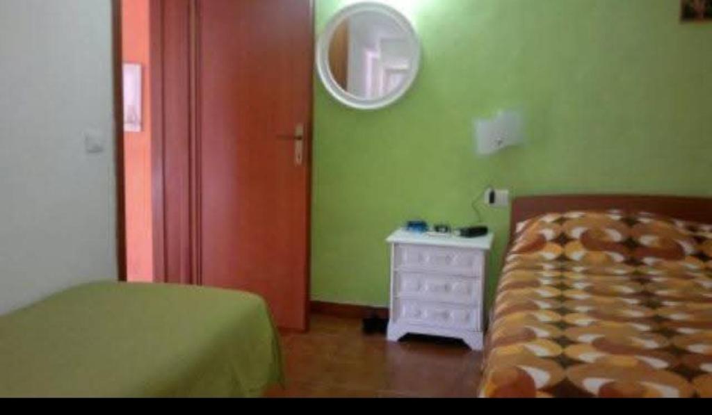 a bedroom with green walls and a bed and a mirror at Affittasi casa Fetovaia Isola D'Elba in Fetovaia