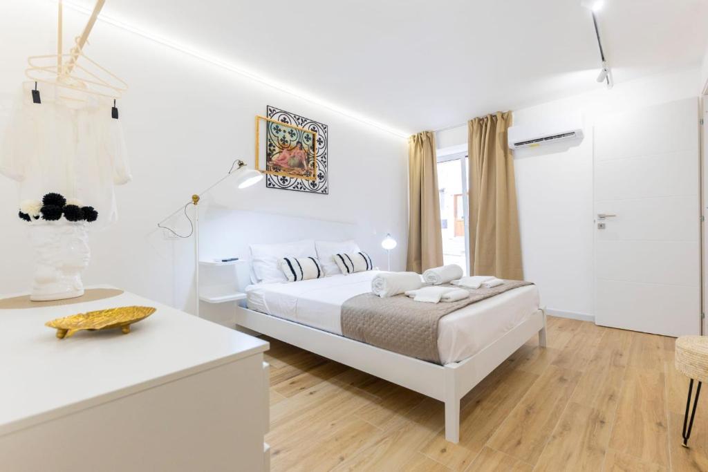 a white bedroom with a bed and a table at Casa Zio Lele in Cefalù