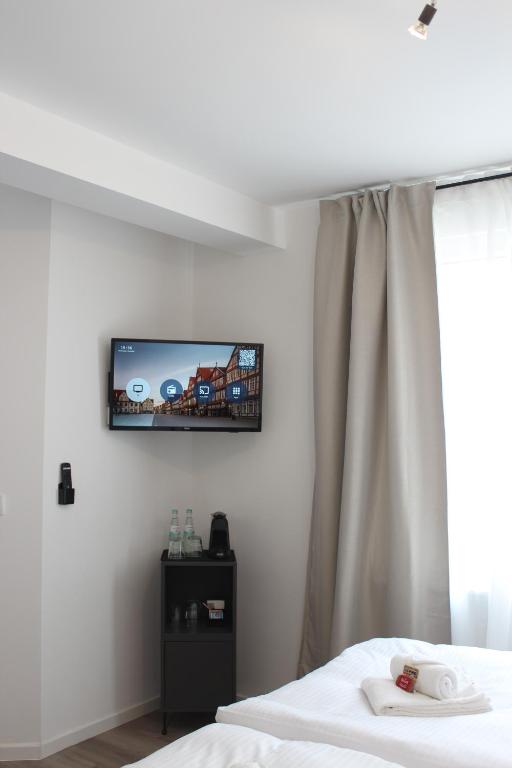 ツェレにあるBoutique Hotel - Celler Altstadtのベッドと壁にテレビが掛かった寝室