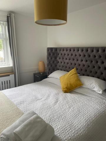 a bedroom with a large bed with a yellow pillow at Modern flat in quiet residential cul-de-sac in Kilwinning