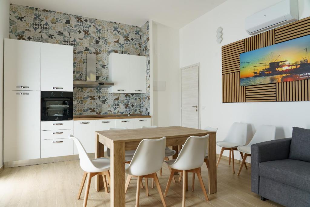 a kitchen with a wooden table and white chairs at Costa d'Abruzzo - Casa Vacanza in Montesilvano
