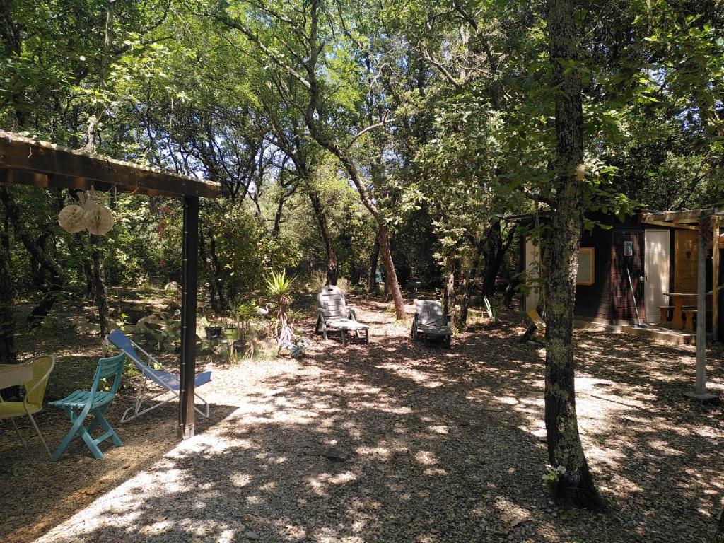 une cour avec une tente, des chaises et des arbres dans l'établissement Le chalet dans les bois, à Lecques
