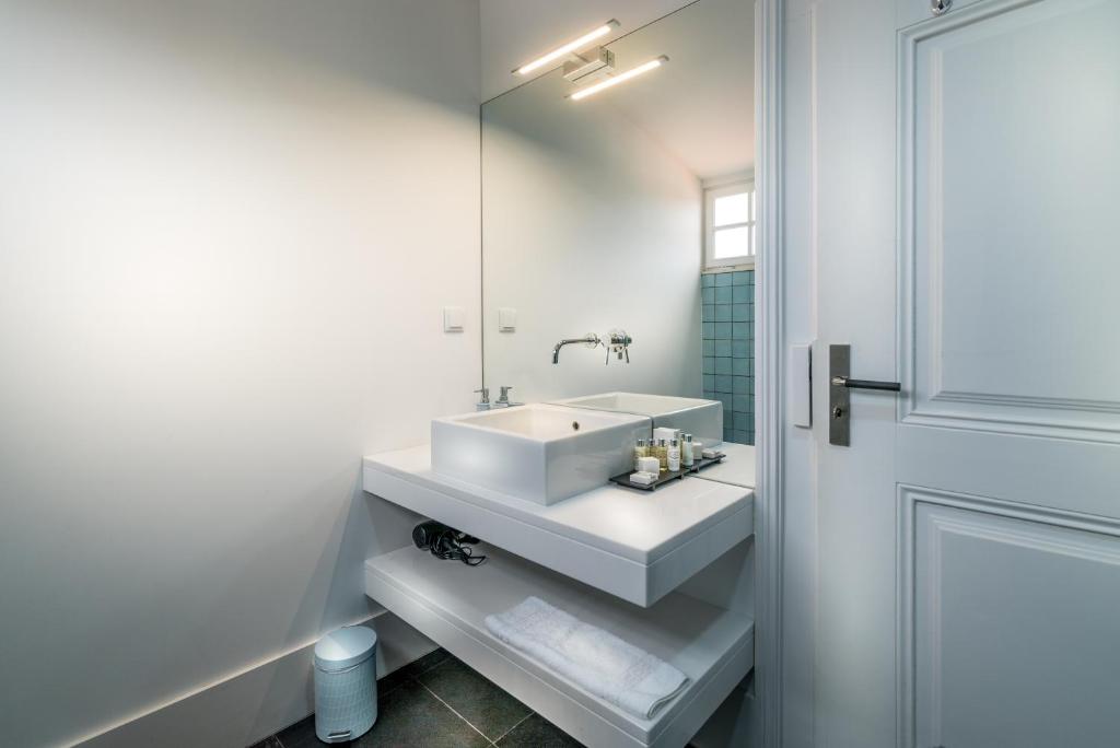 a white bathroom with a sink and a mirror at Villa Vasco da Gama in Cascais