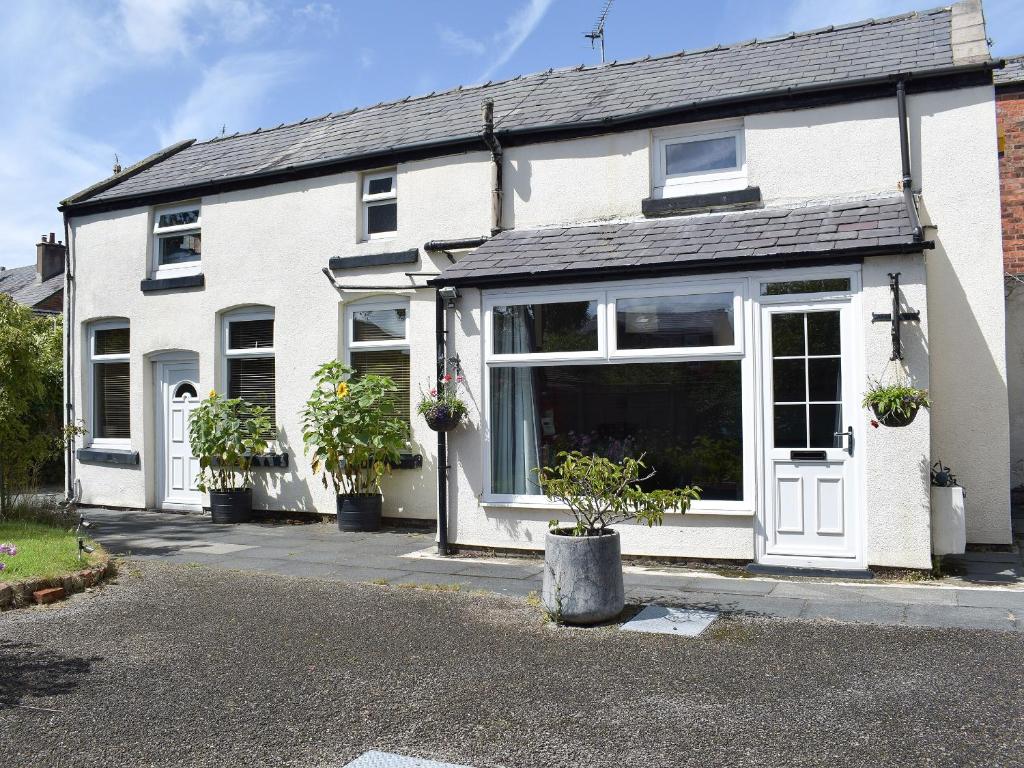 a white house with potted plants in front of it at The Cottage At Stanley Villa in Southport
