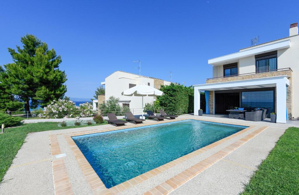 a swimming pool in front of a house at Pentanemi Luxury Villa in Hanioti