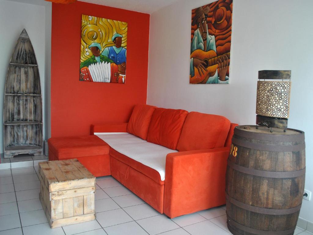 a living room with an orange couch and a barrel at CoCoKreyol - " ARUBA" in Les Trois-Îlets