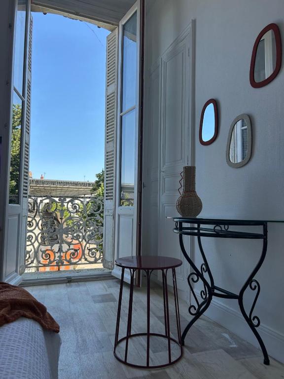 a bedroom with a table and a view of a balcony at L'Oasis - Halles Châtellerault in Châtellerault