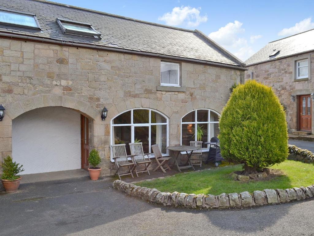 an external view of a house with a table and chairs at The Granary Cottage in Warenford