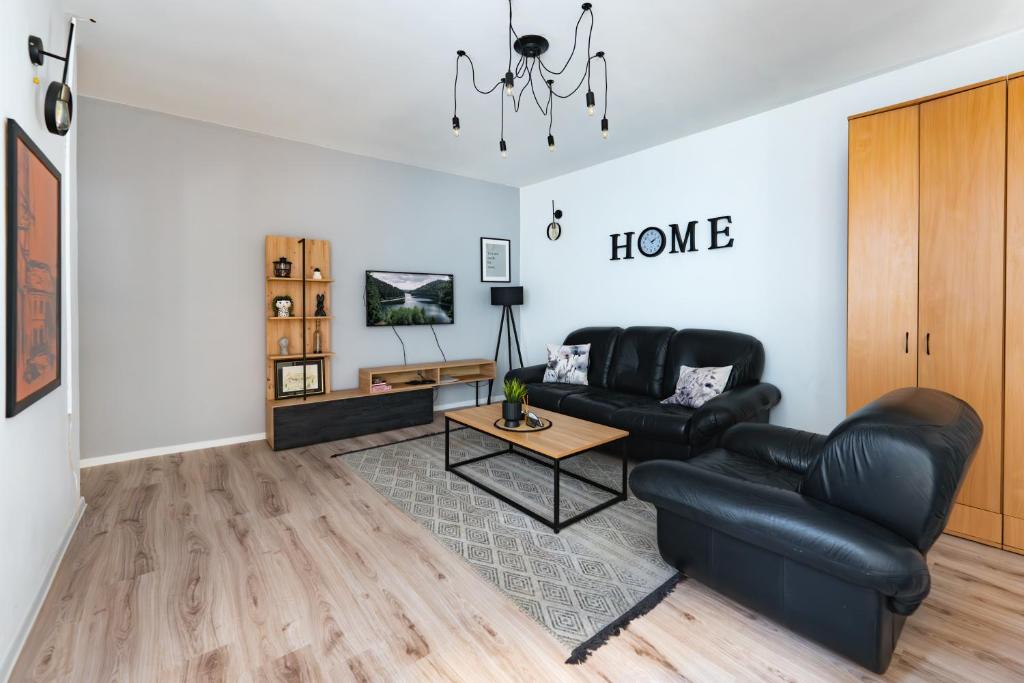 a living room with a black leather couch and a table at Industrial Home Vršac in Vršac