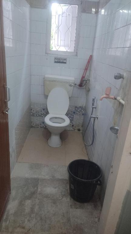a bathroom with a toilet and a window and a bucket at Namaskar Lodge and Homestay in Guwahati