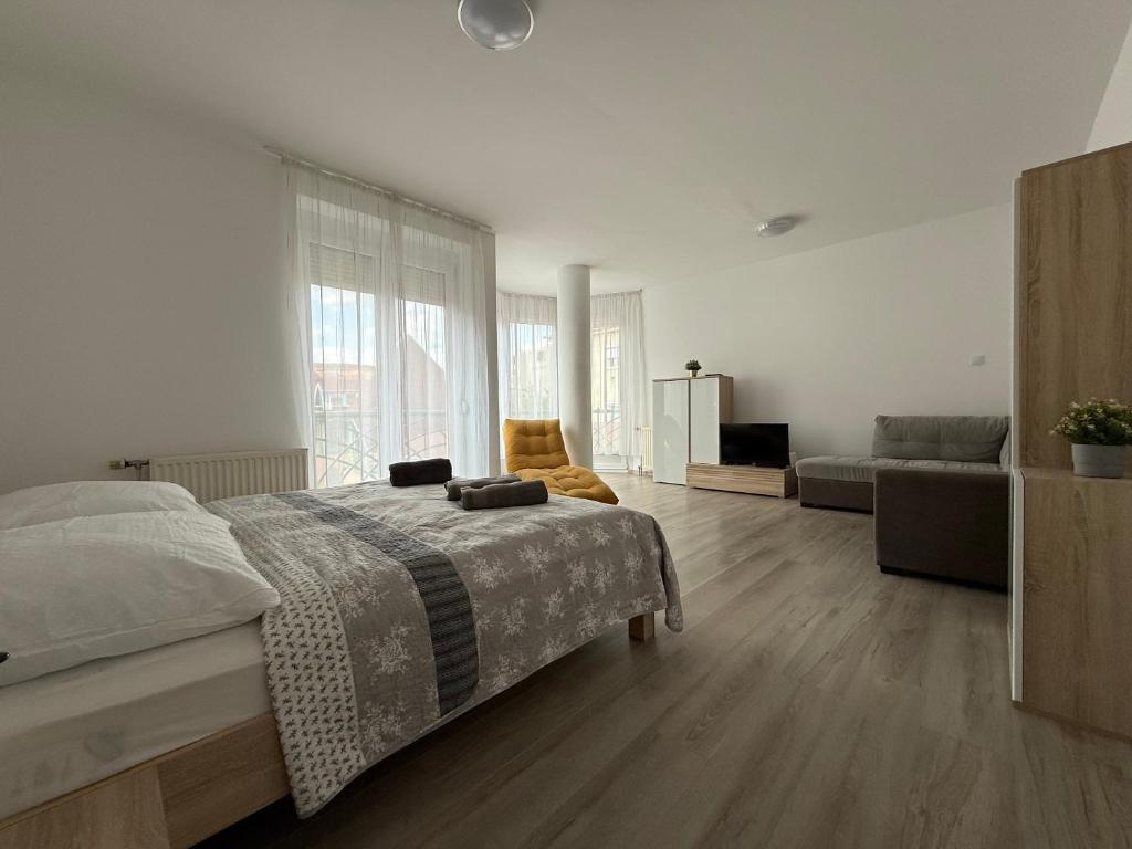ein weißes Schlafzimmer mit einem Bett und einer Couch in der Unterkunft F25 Apartman in Pécs