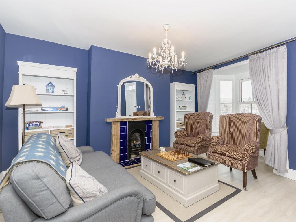 a blue living room with a couch and a fireplace at Frankland House in Whitby