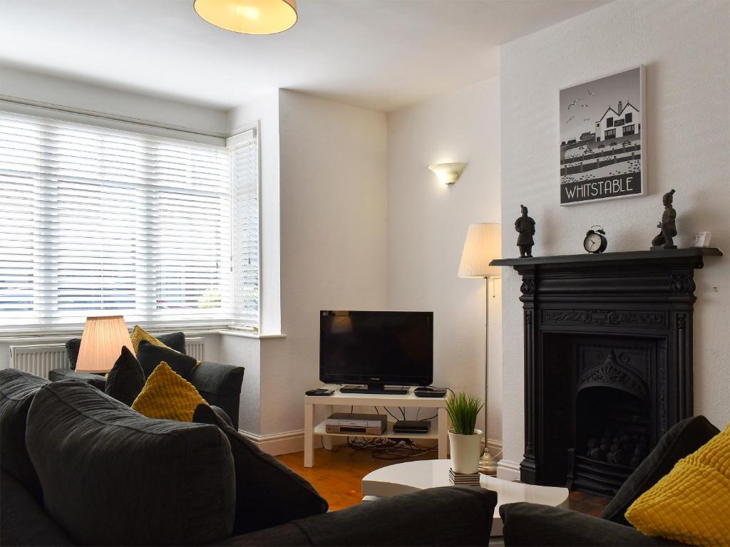 a living room with a fireplace and a television at Shingle Cottage in Whitstable
