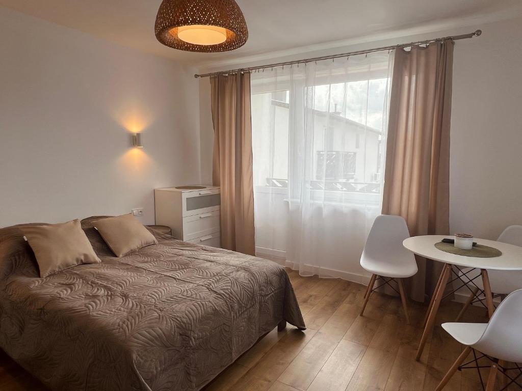 a bedroom with a bed and a table and a window at Pokoje Gościnne REST in Karwia