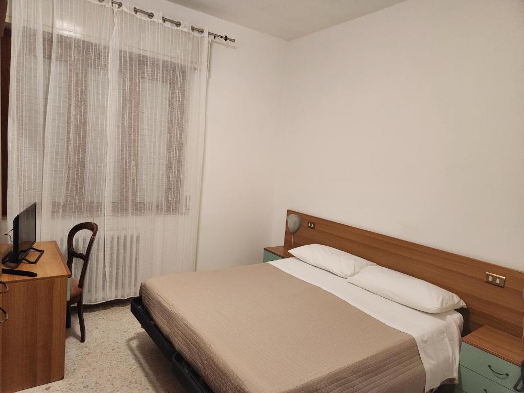 Un dormitorio con una cama y un escritorio y una ventana. en Albergo Gemma, en Roseto degli Abruzzi