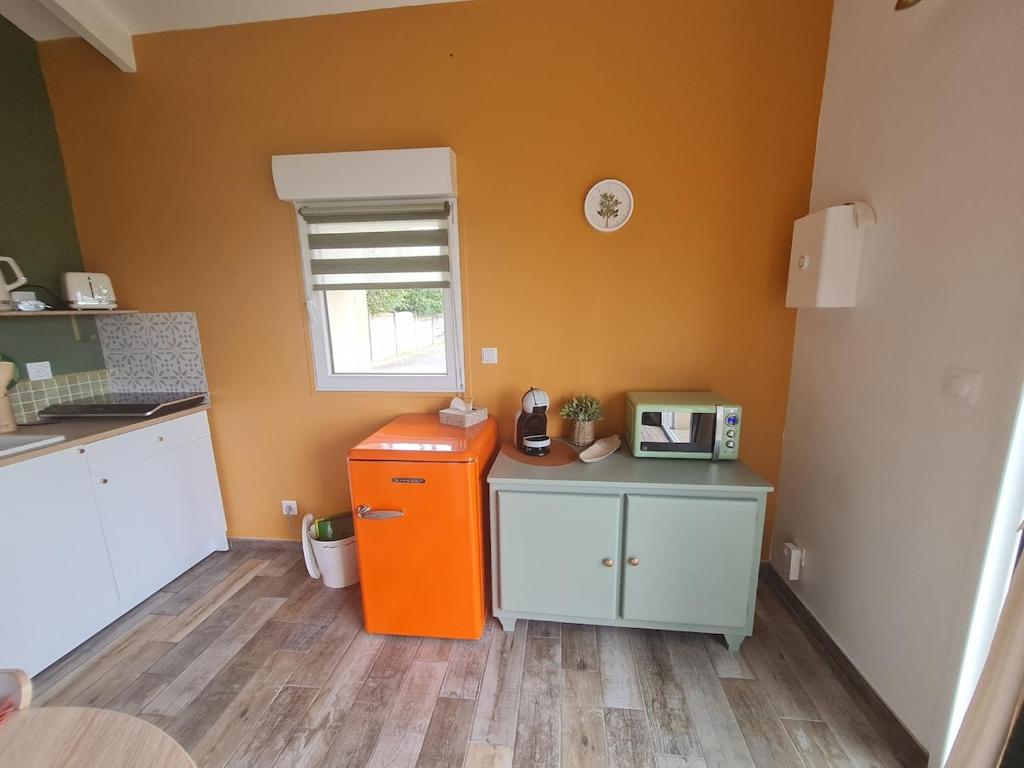 a kitchen with an orange refrigerator in a room at Dépendance entre CAEN et la mer in Lasson