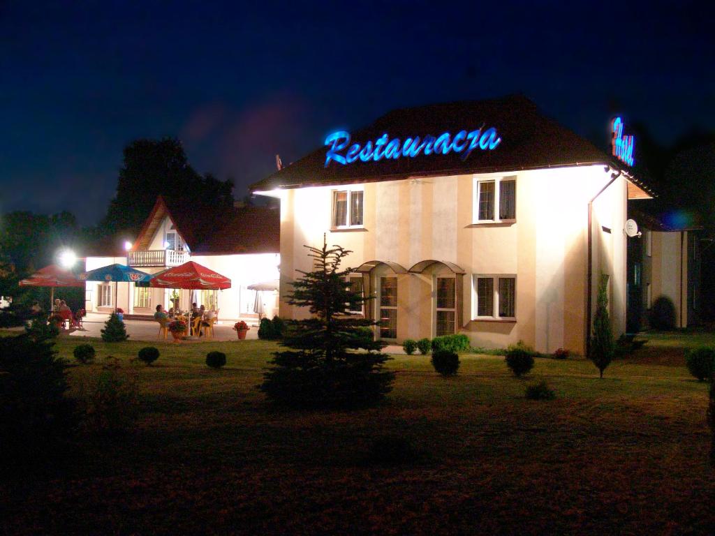 a building with a neon sign on it at night at Hotel Pod Dębami in Pabianice