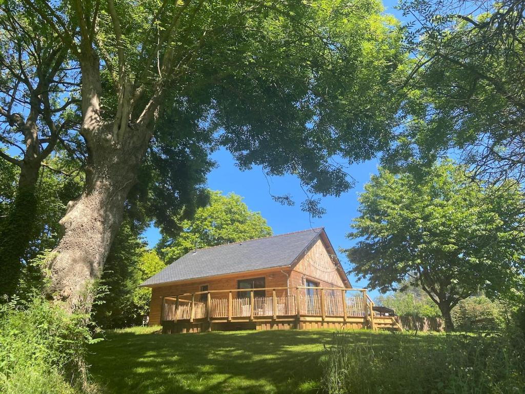 une grande maison en bois avec une grande terrasse sur un terrain dans l'établissement La campagne à 500m de la plage, à Plouha