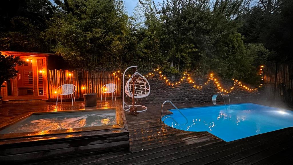 ein Hinterhof mit einem Pool mit Stühlen und einem Zaun mit Lichtern in der Unterkunft Hotel Lagoluz in Pucón