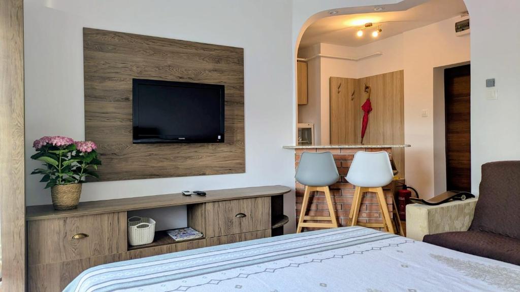 ソバタにあるVÉGH Apartmanのベッドとテレビと椅子2脚のある部屋