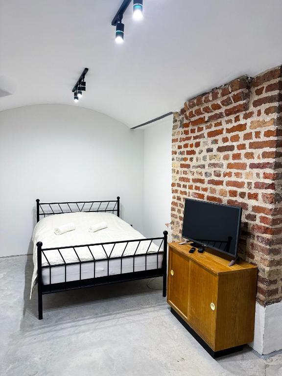 a bedroom with a bed and a tv and a brick wall at Wagners Refuge 3 in Riga