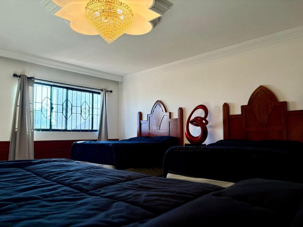 a bedroom with two beds and a chandelier at Domus Áurea in Mazatlán