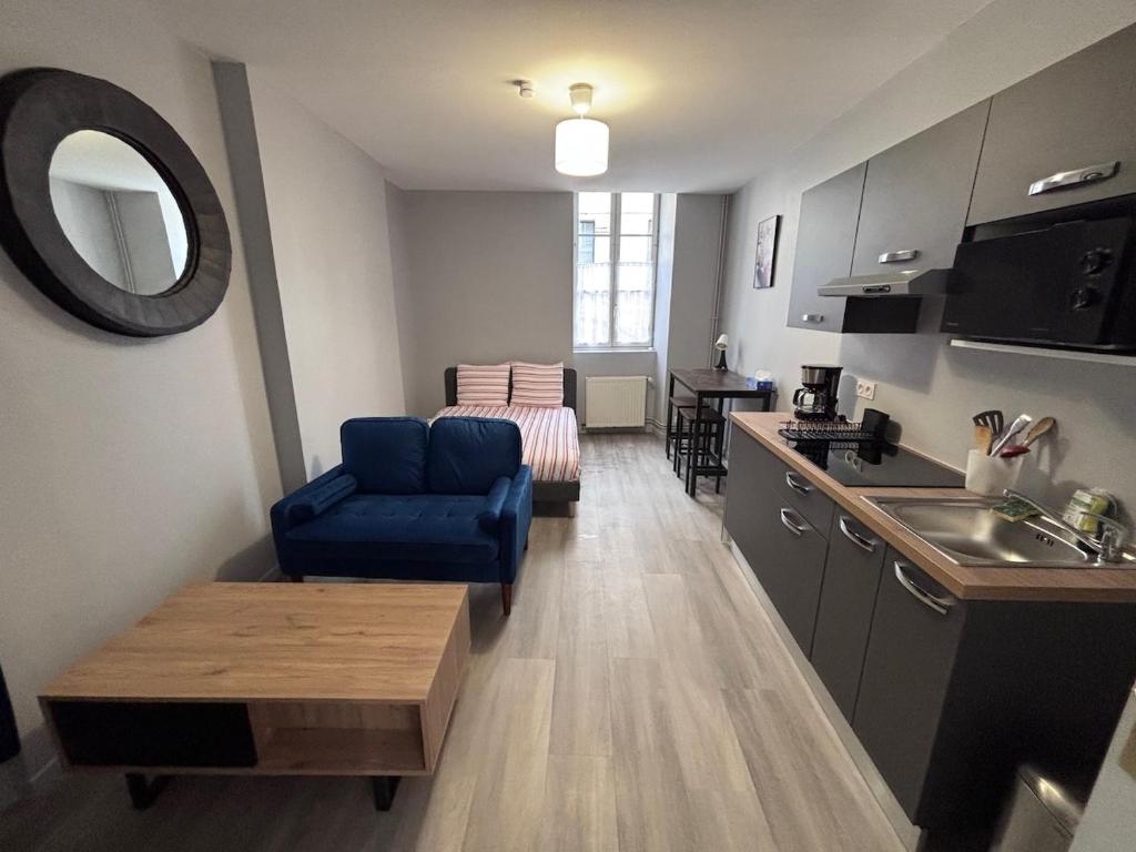 un salon avec une chaise bleue et une cuisine dans l'établissement Studio rénové - Centre Ville de semur, à Semur-en-Auxois