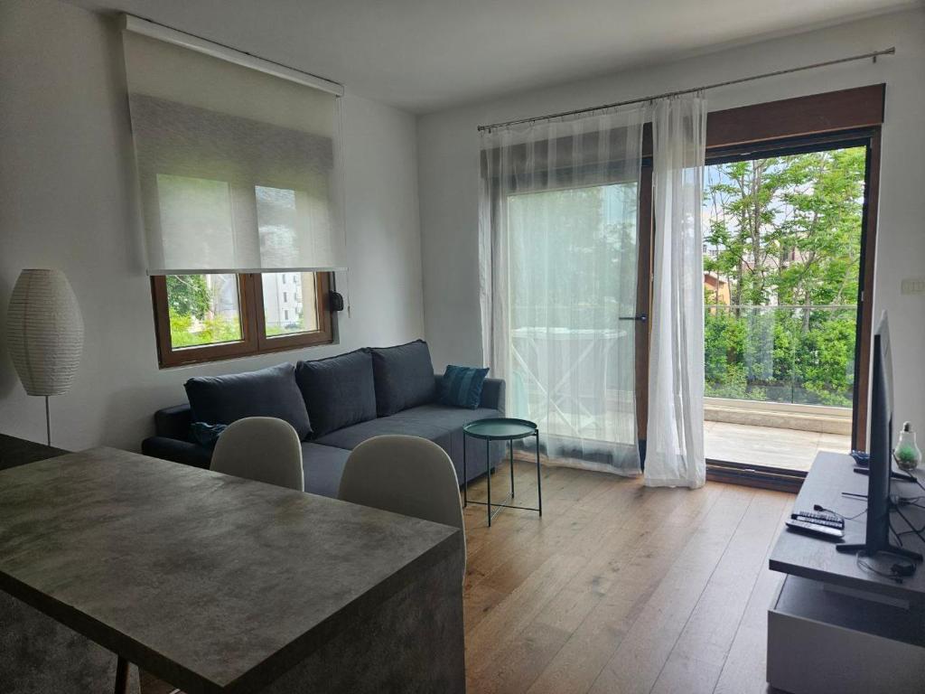 a living room with a blue couch and a large window at Lazure apartment in Tivat