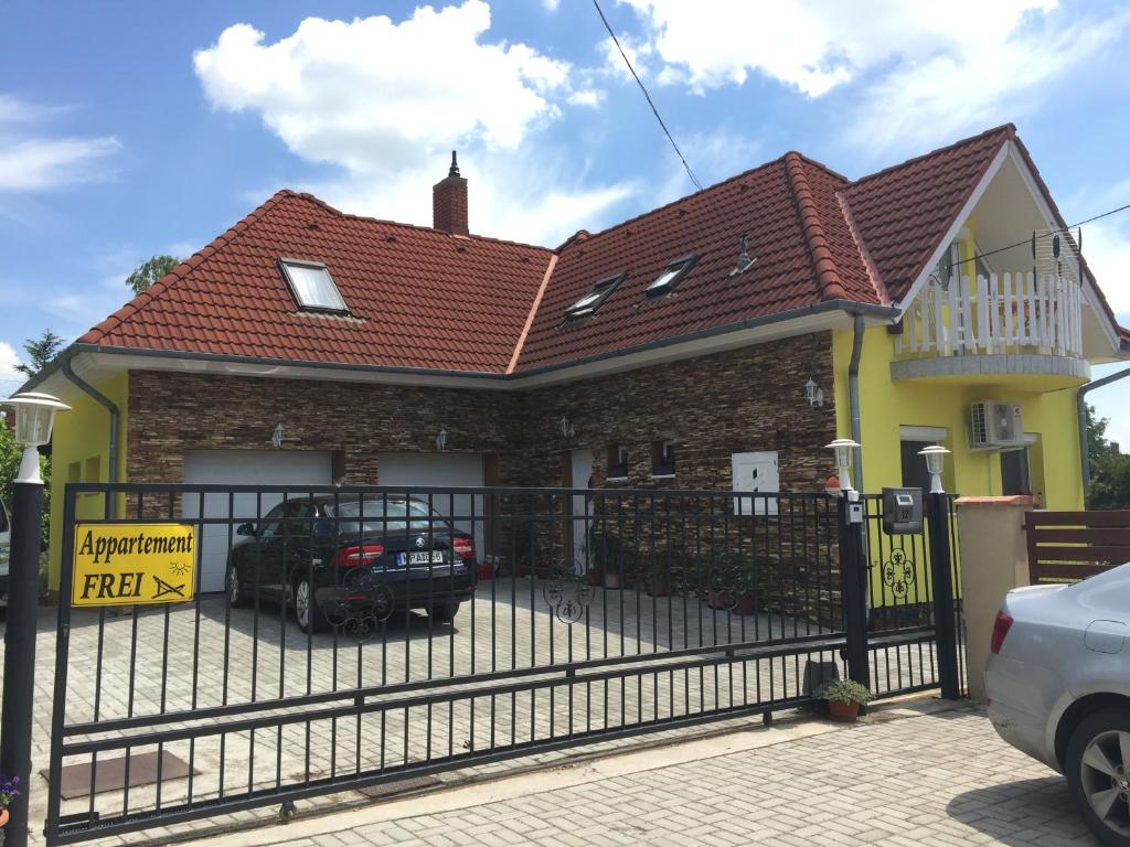 a house with a gate and a car parked in front at Csikós Apartman in Gyenesdiás