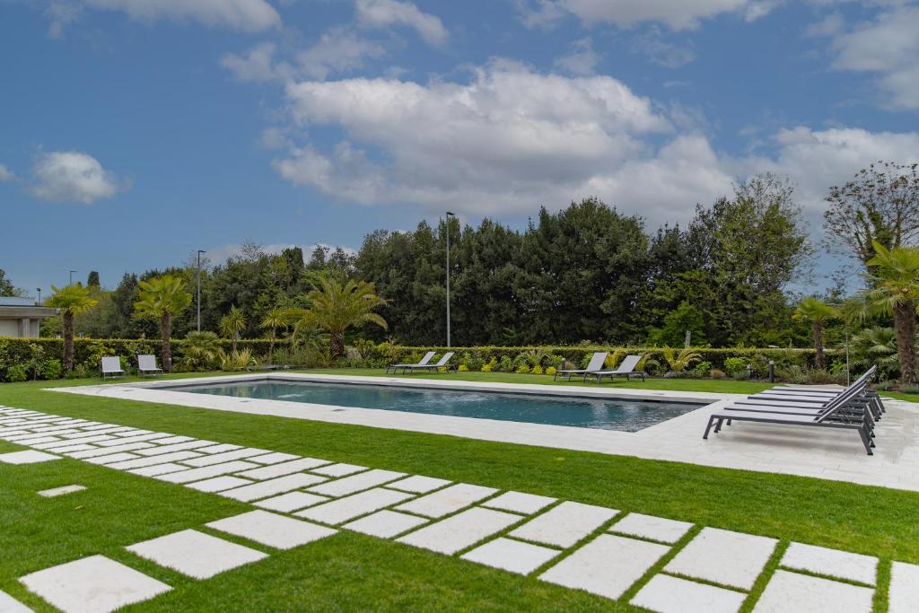a swimming pool with a bench and grass at Villa Dama Holiday Apartments in Padenghe sul Garda