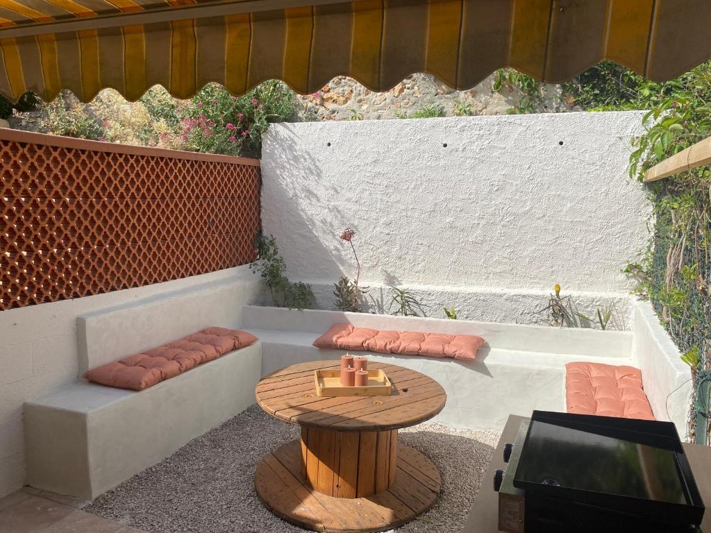 un petit patio avec une table, des bancs et une télévision dans l'établissement Maisonnette climatisée à louer 5 nuits minimum dans résidence fermée proche mer, à Bandol