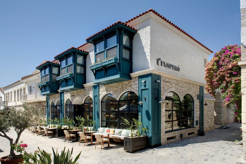 a building with tables and chairs outside of it at Tinspiro Alaçatı in Alacati