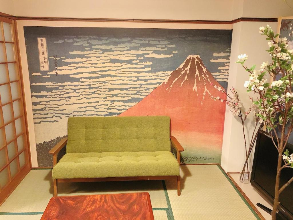 a living room with a green couch and a mountain mural at Station Front JUSO EAST 402 No Lift in Osaka