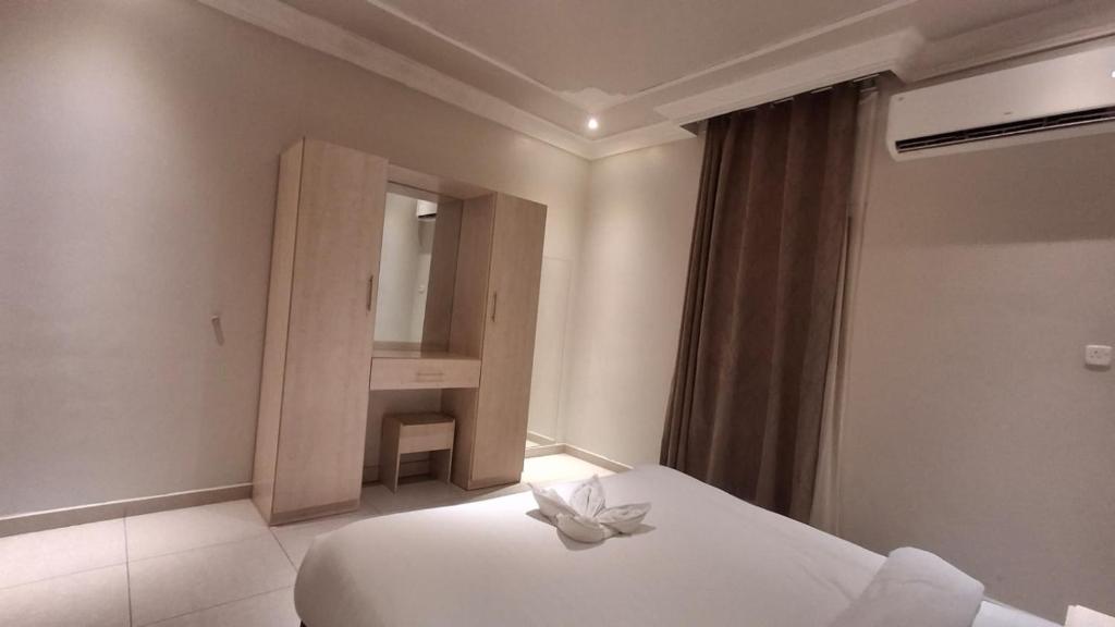 a bedroom with a white bed and a mirror at Yellow Rose Taif Hotel Apartments in Taif