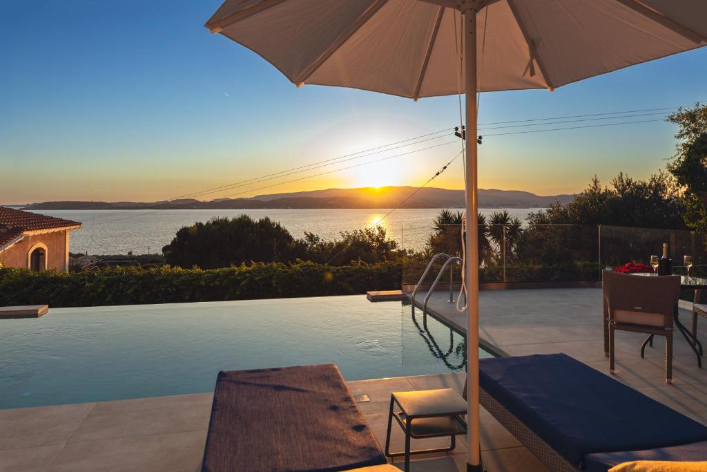a patio with an umbrella and a swimming pool at Am Meer Suite in Argostoli
