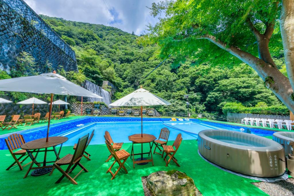 a pool with tables and chairs and umbrellas at Hotel Okuyumoto in Hakone