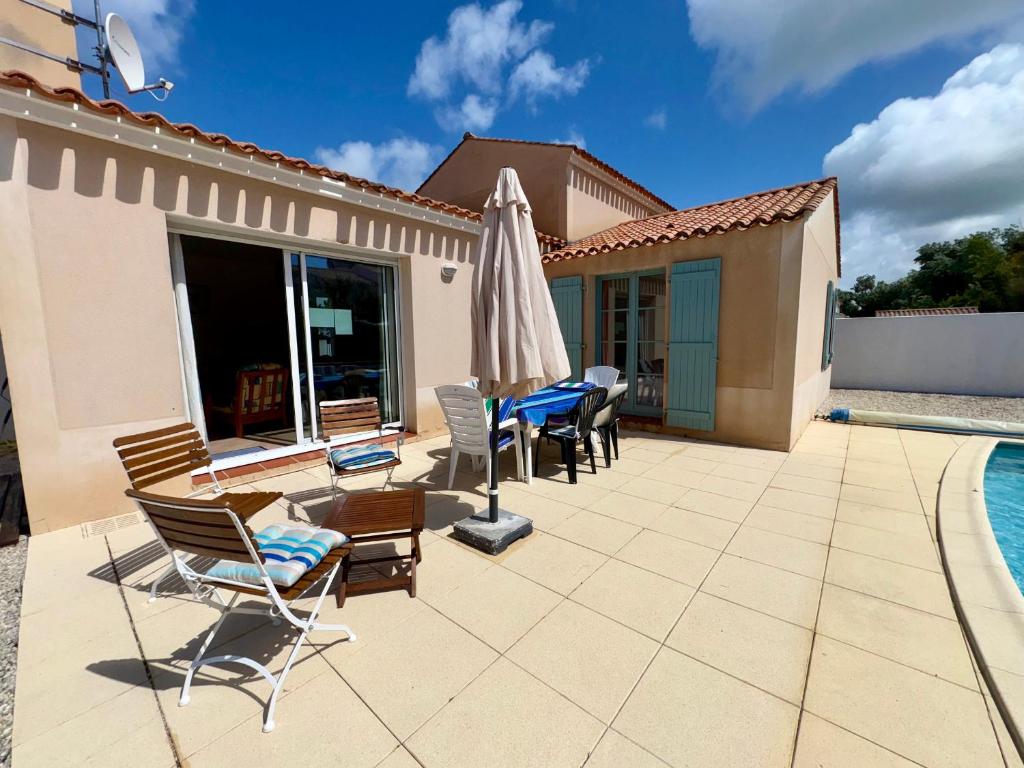 une terrasse avec des chaises et un parasol ainsi qu'une piscine dans l'établissement Maison charmante pour 6 pers. dans résidence calme avec piscine privée - FR-1-323-580, à Saint-Jean-de-Monts