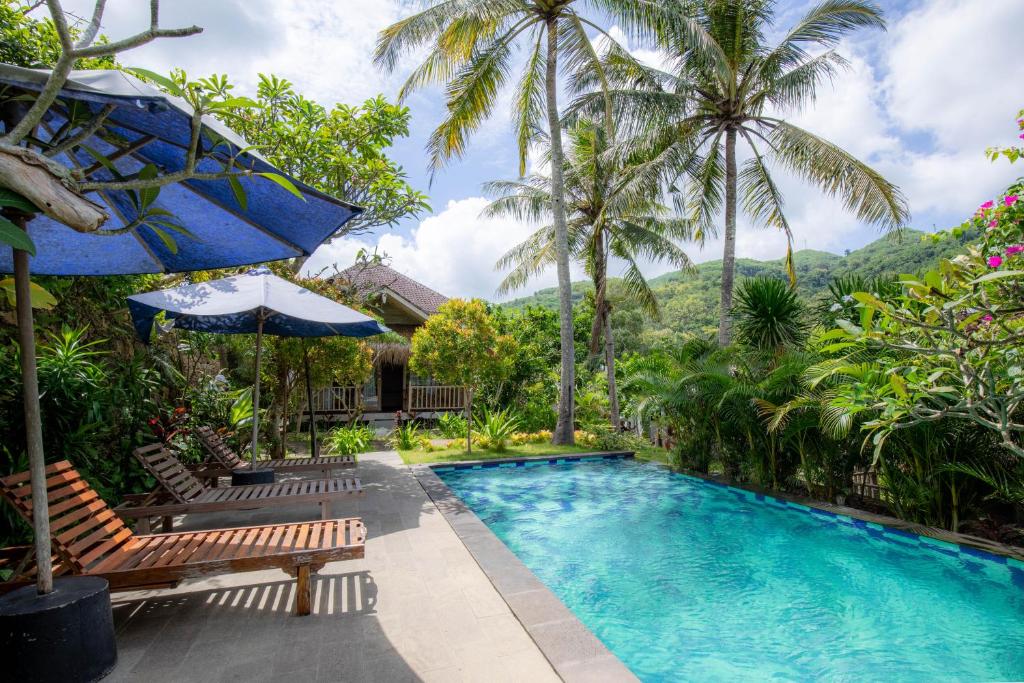 a swimming pool in a resort with palm trees at Bhavana Cottage in Nusa Penida